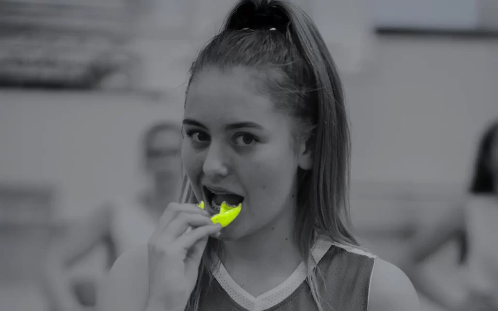 A female sports person playing sport with braces and a protective NeoMorph Lime Green Mouthguard