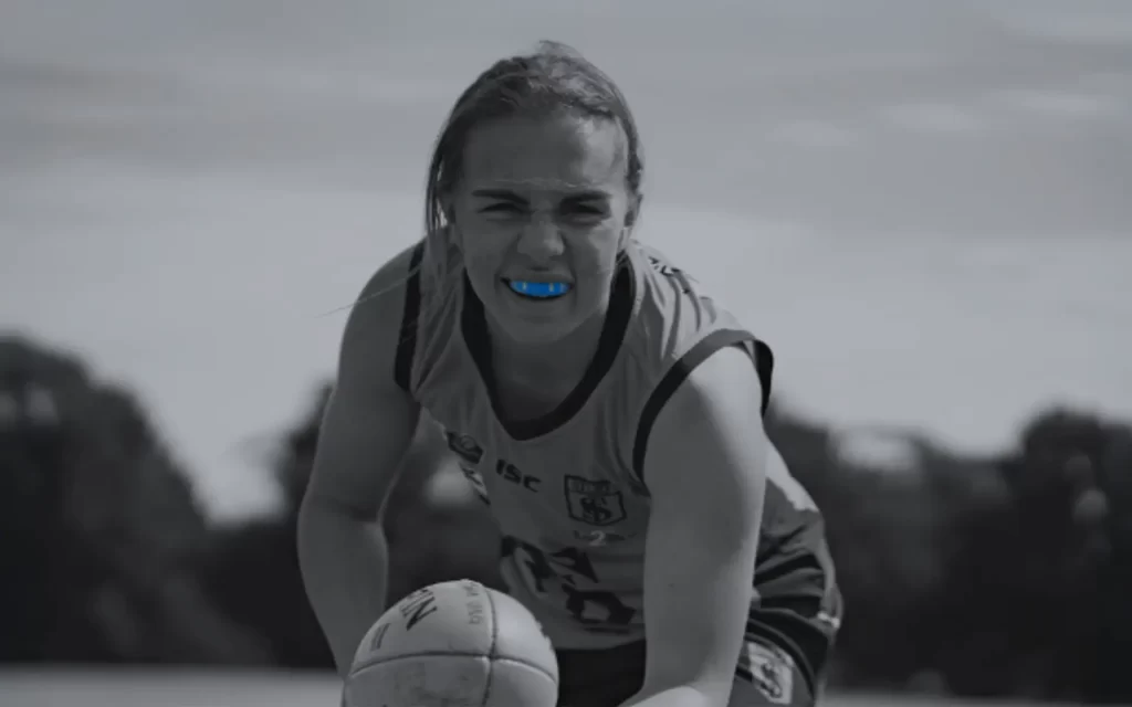 A female sports person handballing an Australian rules football